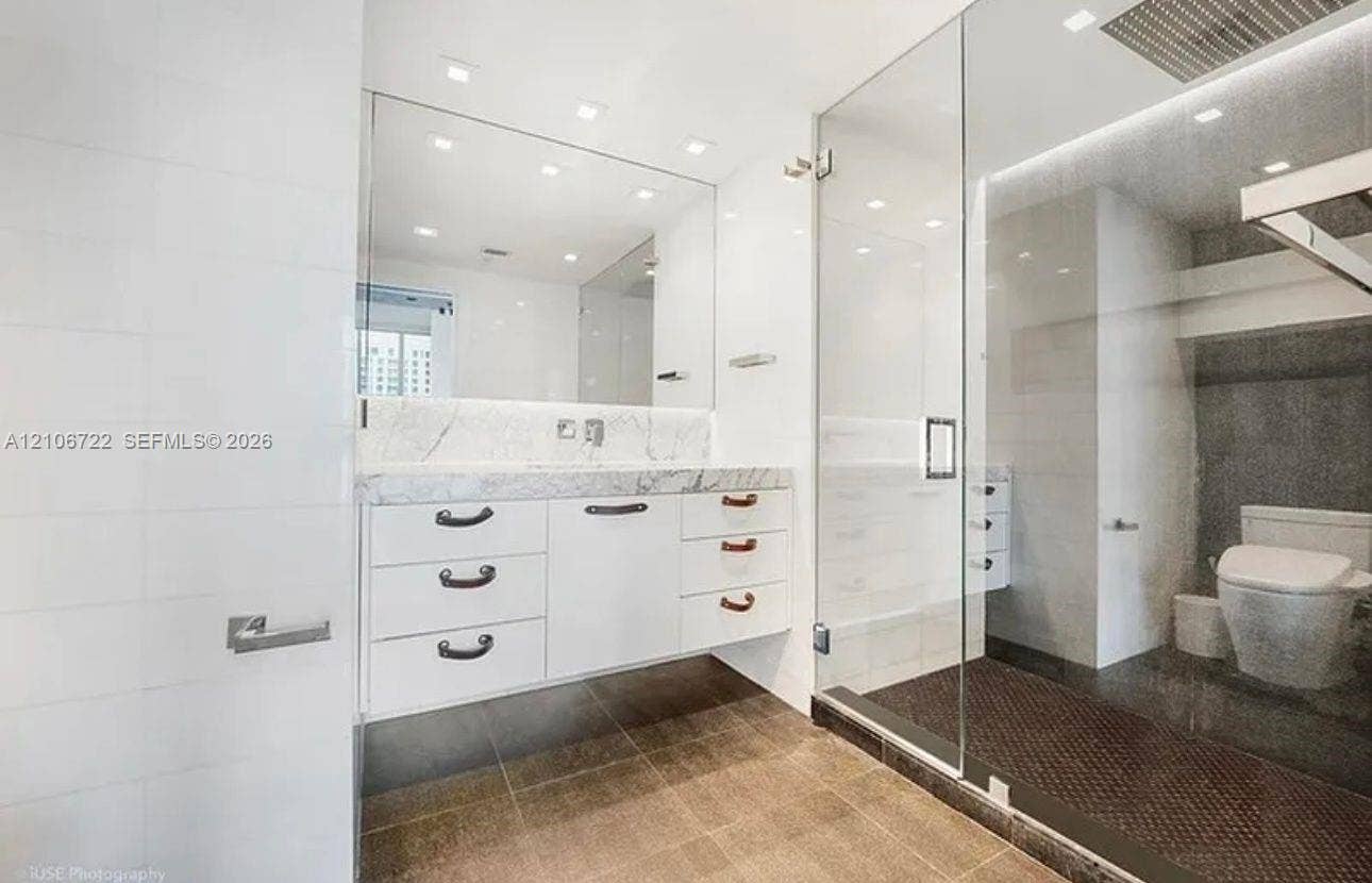 480 NE 30th Street, #1005, Miami, FL 33137 Floating white vanity featuring a stone countertop, wall-to-wall mirror, glass-enclosed shower, recessed ceiling lighting, and large-format floor tiling