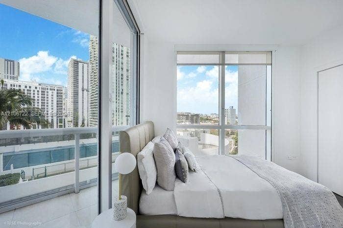 480 NE 30th Street, #1005, Miami, FL 33137 Floor-to-ceiling windows, high-rise urban scenery, glass-paneled balcony, and neutral tile flooring