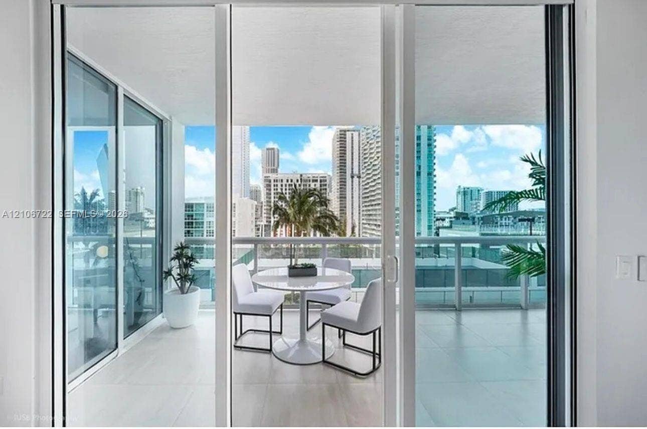 480 NE 30th Street, #1005, Miami, FL 33137 Covered balcony featuring oversized floor-to-ceiling sliding glass doors, neutral tile flooring, and a glass-paneled railing