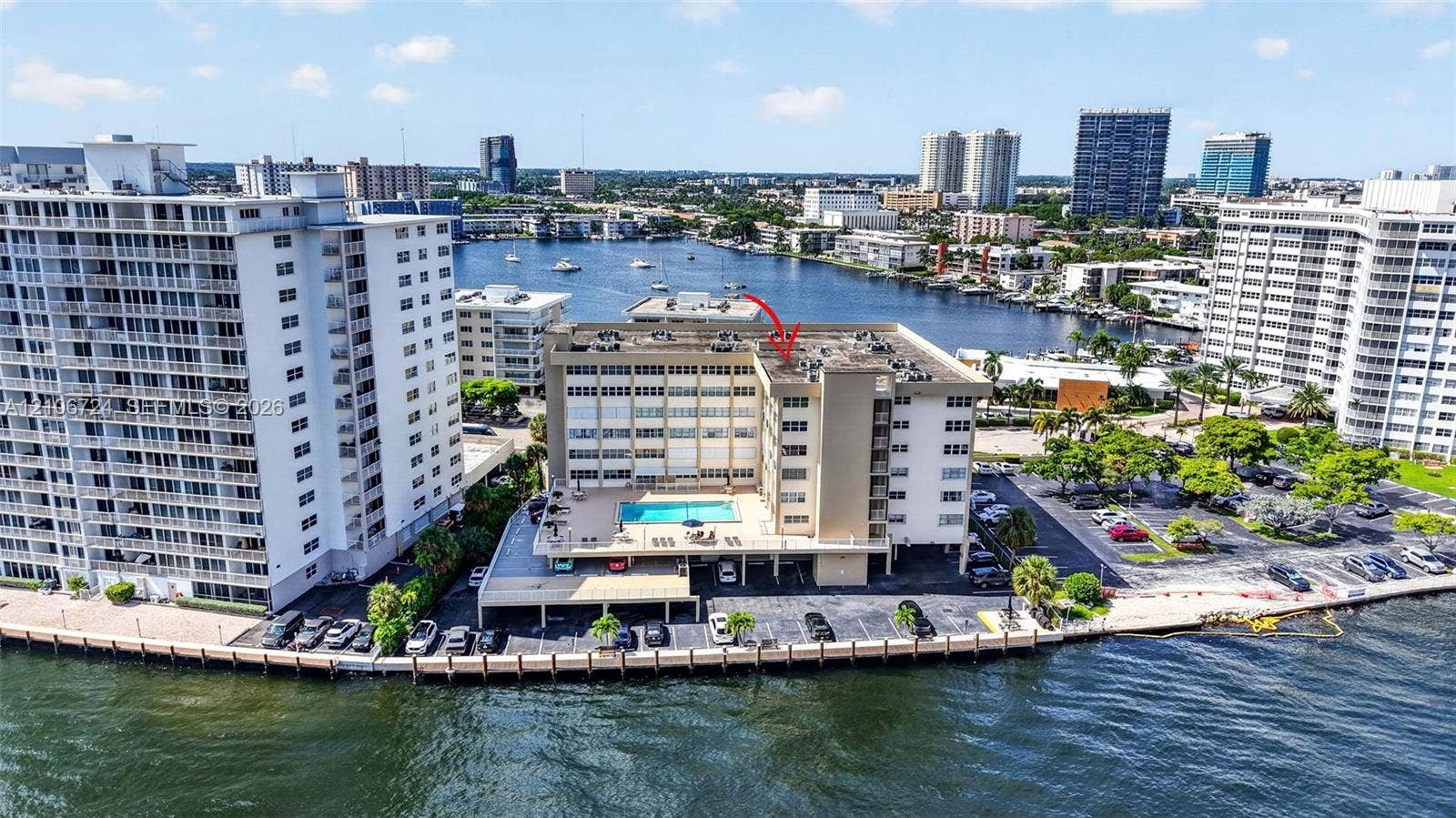 111 Golden Isles Drive, #G12, Hallandale Beach, FL 33009 Mid-rise waterfront multi-story building featuring an elevated exterior pool deck, covered parking, and direct water frontage