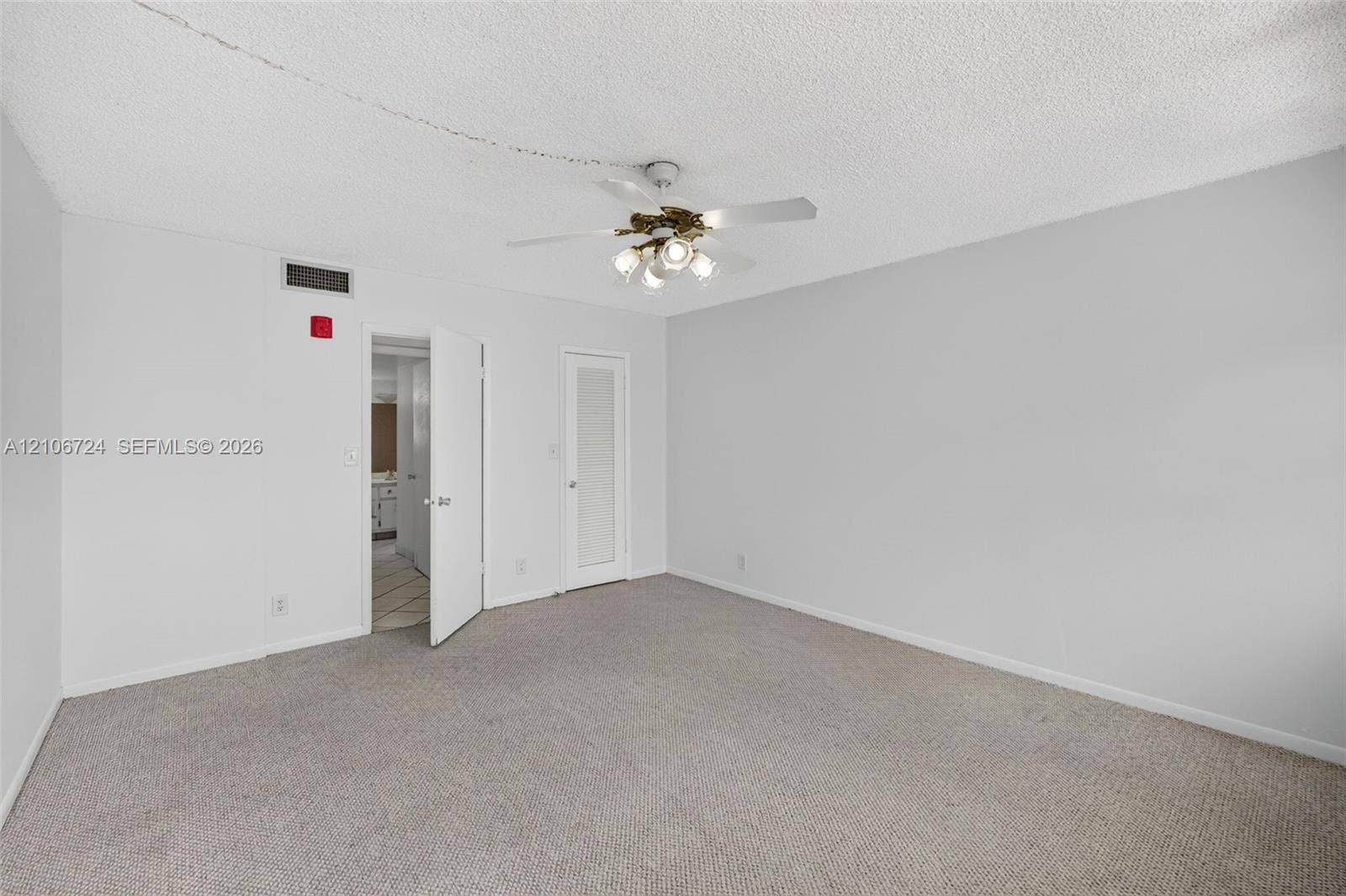 111 Golden Isles Drive, #G12, Hallandale Beach, FL 33009 Neutral-toned carpeted flooring, textured ceiling, and four-blade ceiling fan with integrated multi-bulb light fixture
