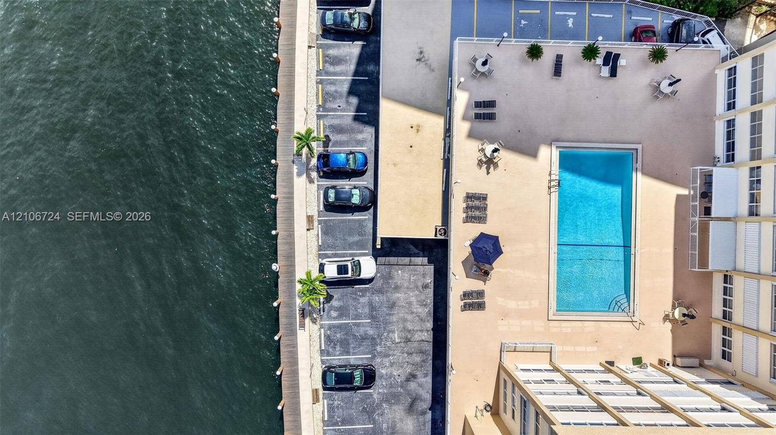 111 Golden Isles Drive, #G12, Hallandale Beach, FL 33009 Waterfront property featuring a rectangular swimming pool, concrete pool deck, and on-site parking area