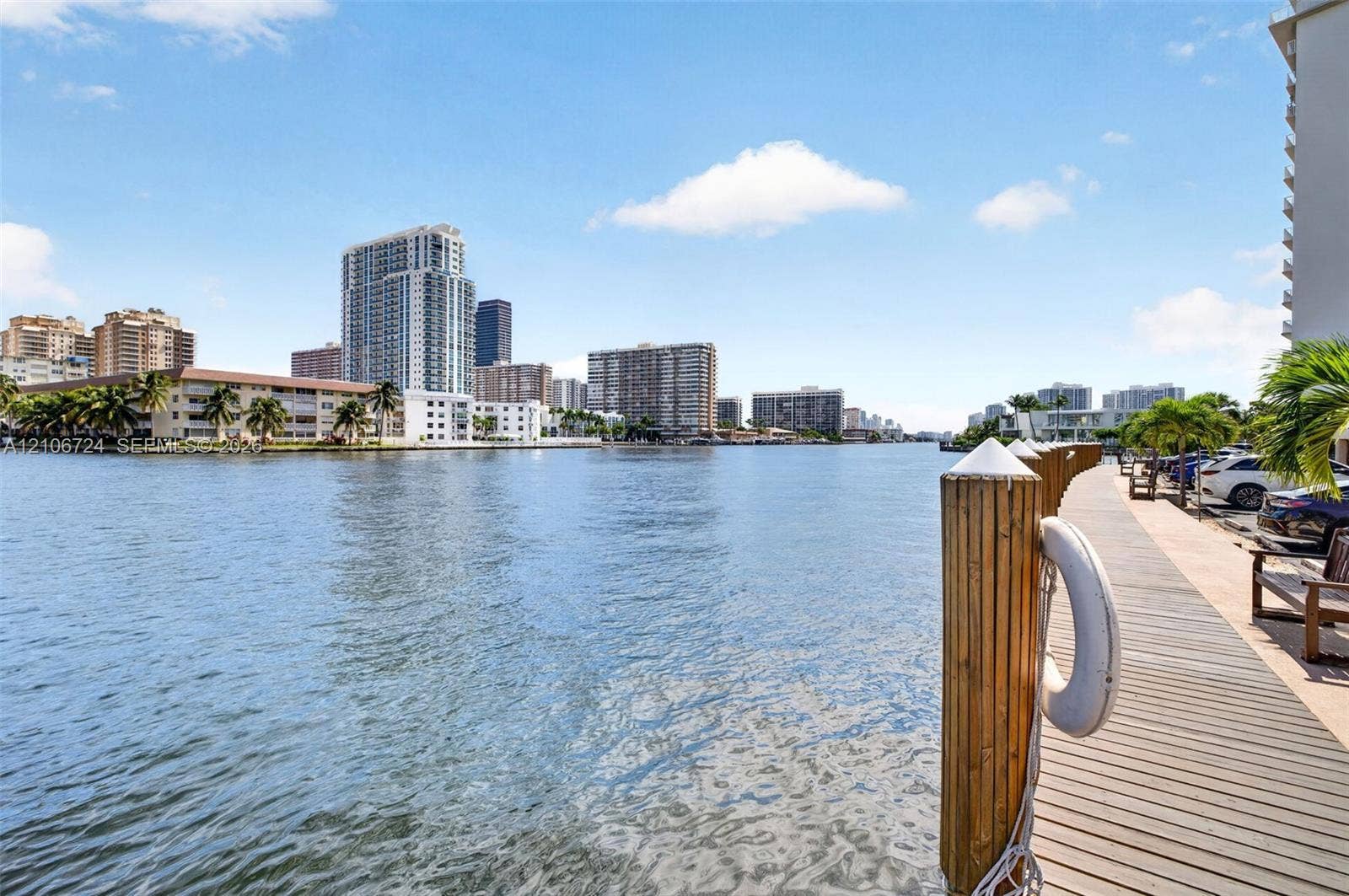 111 Golden Isles Drive, #G12, Hallandale Beach, FL 33009 Waterfront property featuring a wooden bulkhead with pilings and a paved walkway