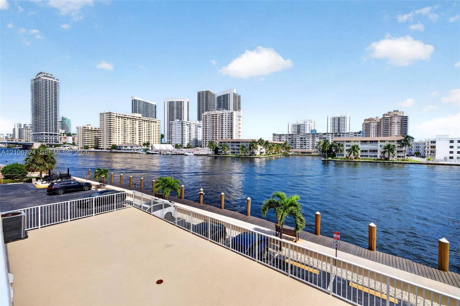 111 Golden Isles Drive, #G12, Hallandale Beach, FL 33009 Elevated outdoor terrace featuring a white metal railing, paved surface, and direct water frontage with a private dock