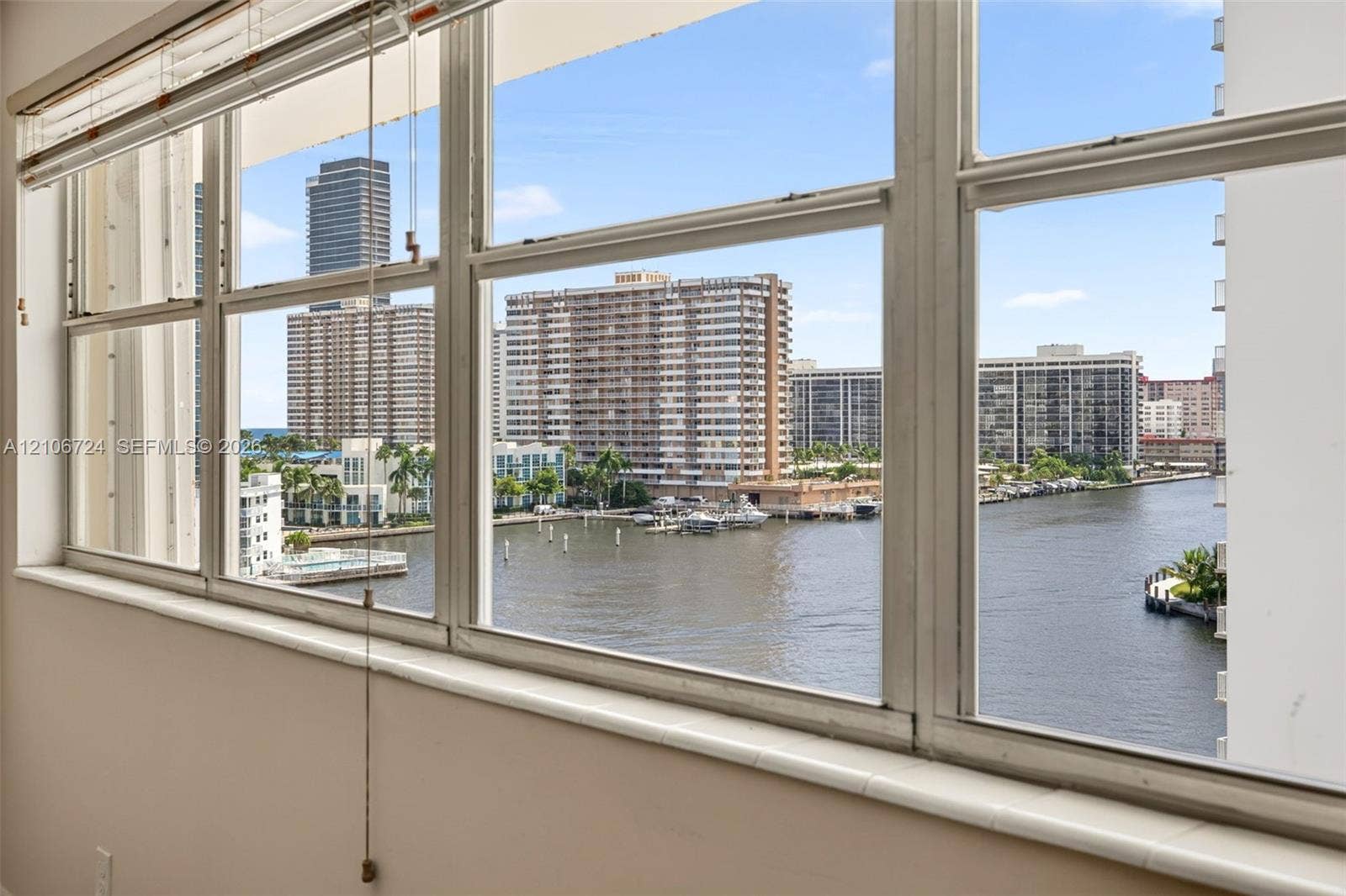 Expansive multi-pane windows featuring deep window sills, overlooking a waterway and urban skyline