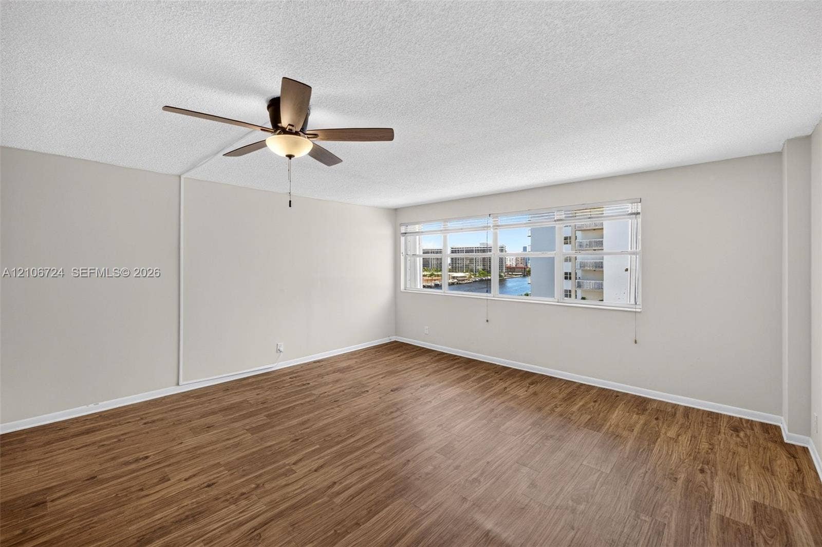 Interior space featuring wood-finish flooring, a multi-pane horizontal window, and a ceiling-mounted fan with integrated lighting