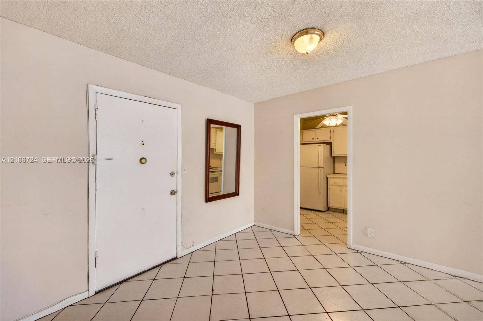 111 Golden Isles Drive, #G12, Hallandale Beach, FL 33009 Ceramic tile flooring arranged in a diagonal pattern, textured ceiling with a dome-style flush-mount light fixture, and an entry door with integrated hardware
