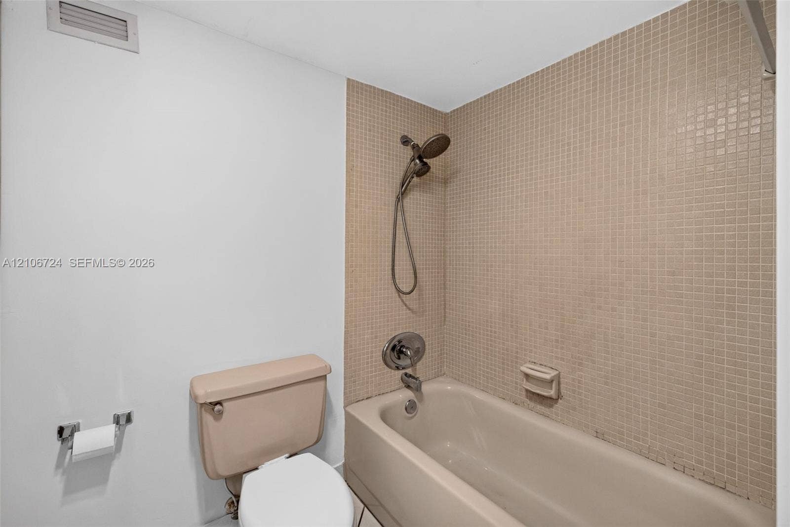 111 Golden Isles Drive, #G12, Hallandale Beach, FL 33009 Bathtub with a shower head, tiled surround, and chrome hardware
