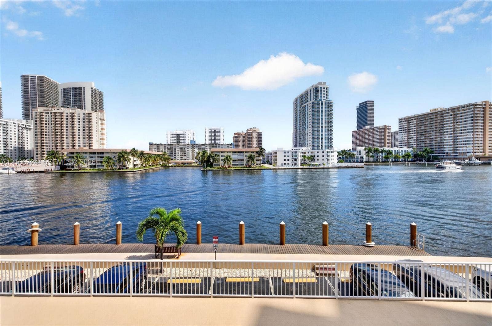 111 Golden Isles Drive, #G12, Hallandale Beach, FL 33009 Waterfront deck featuring a wooden bulkhead, piling moorings, and a metal safety railing