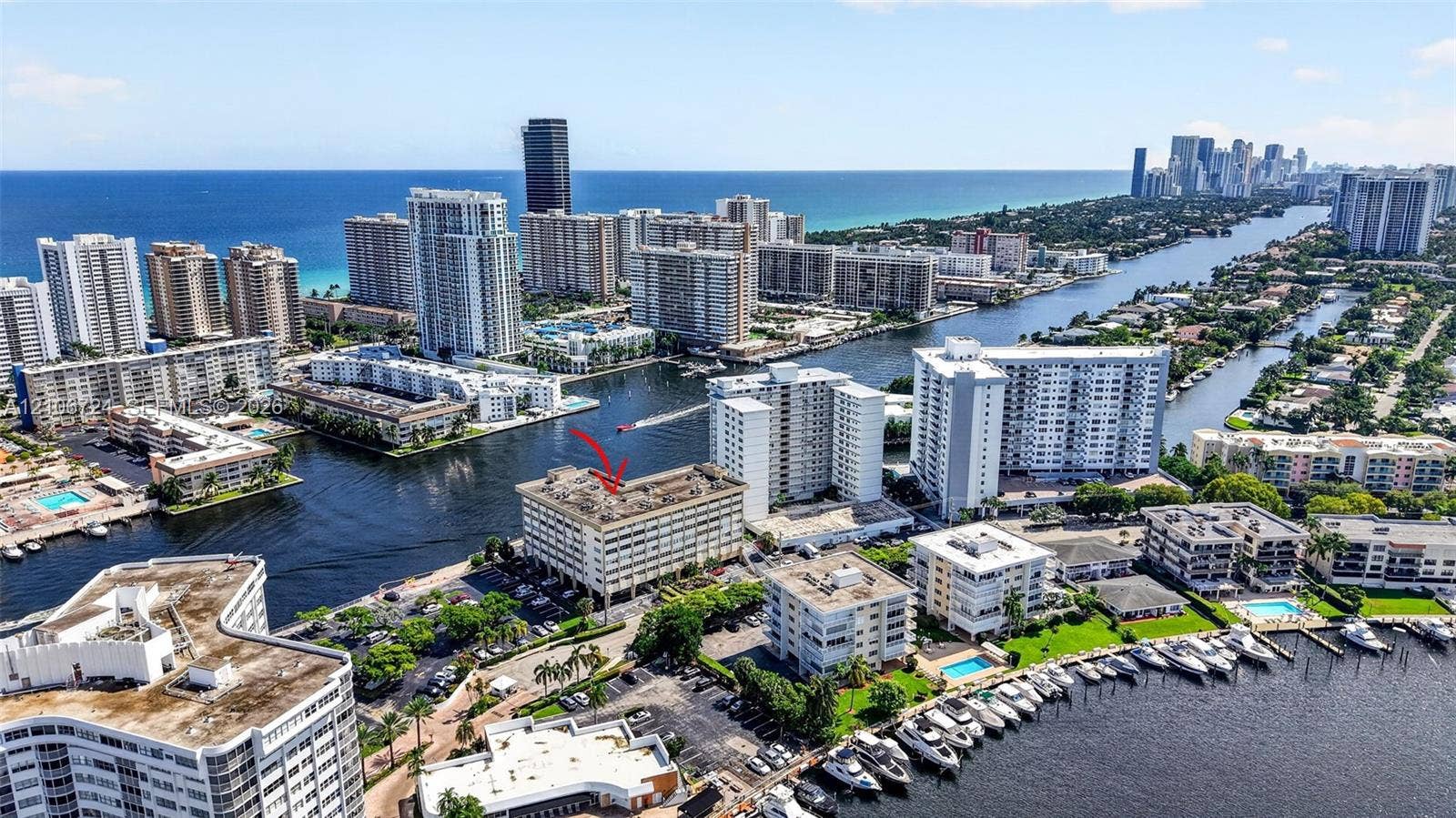 111 Golden Isles Drive, #G12, Hallandale Beach, FL 33009 Aerial perspective of a multi-story waterfront building featuring direct canal access, docking facilities, and proximity to the coastline