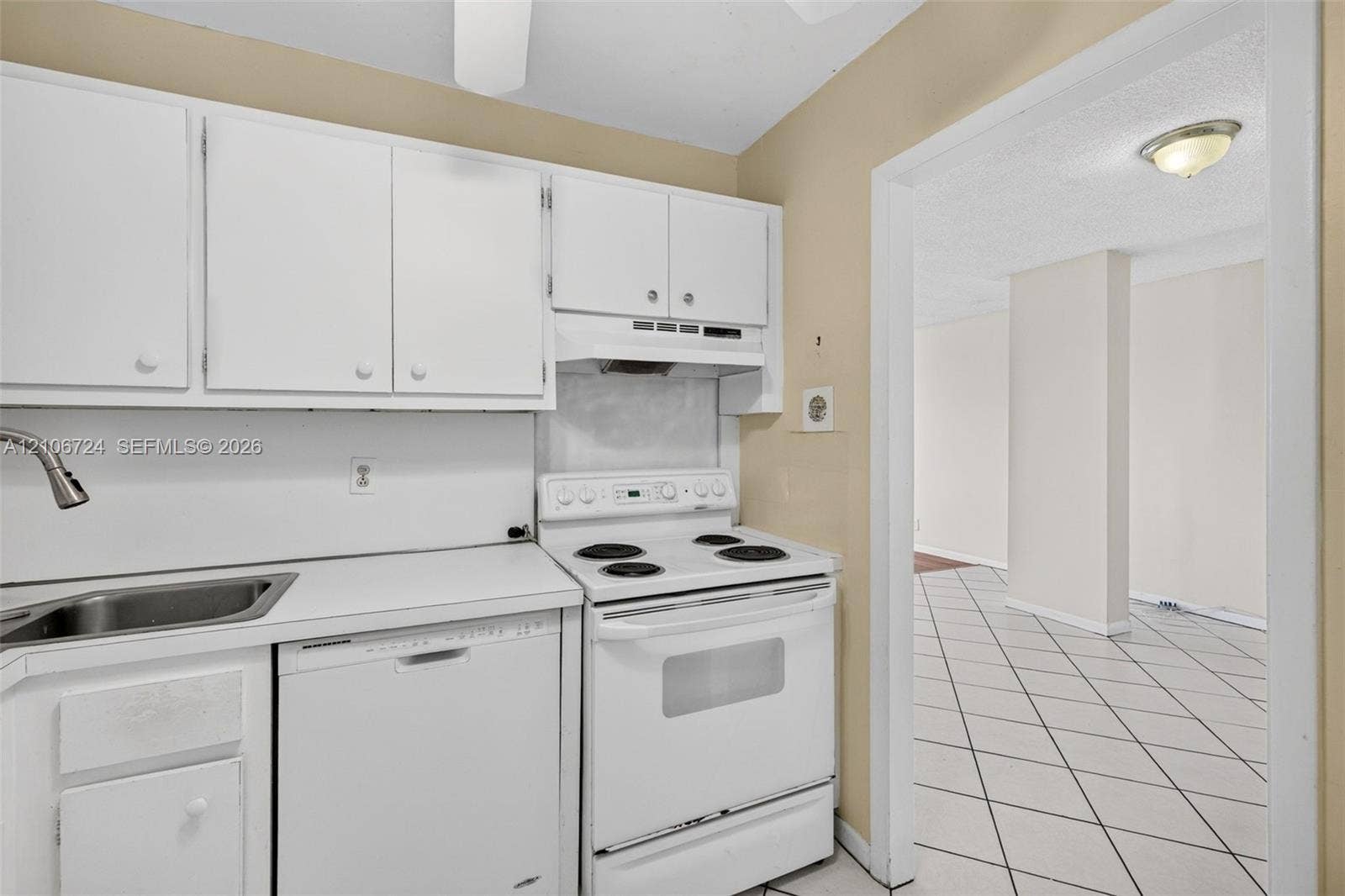 111 Golden Isles Drive, #G12, Hallandale Beach, FL 33009 Kitchen featuring white cabinetry, solid-surface countertops, integrated stainless steel sink with gooseneck faucet, white electric range, and dishwasher