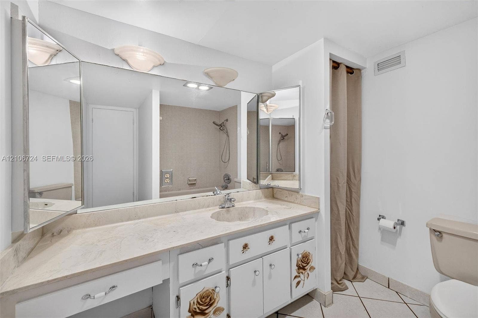 111 Golden Isles Drive, #G12, Hallandale Beach, FL 33009 Bathroom featuring a stone-surface vanity with an integrated basin, a large multi-panel mirror, ceramic tile flooring, and a combined tub and shower surround