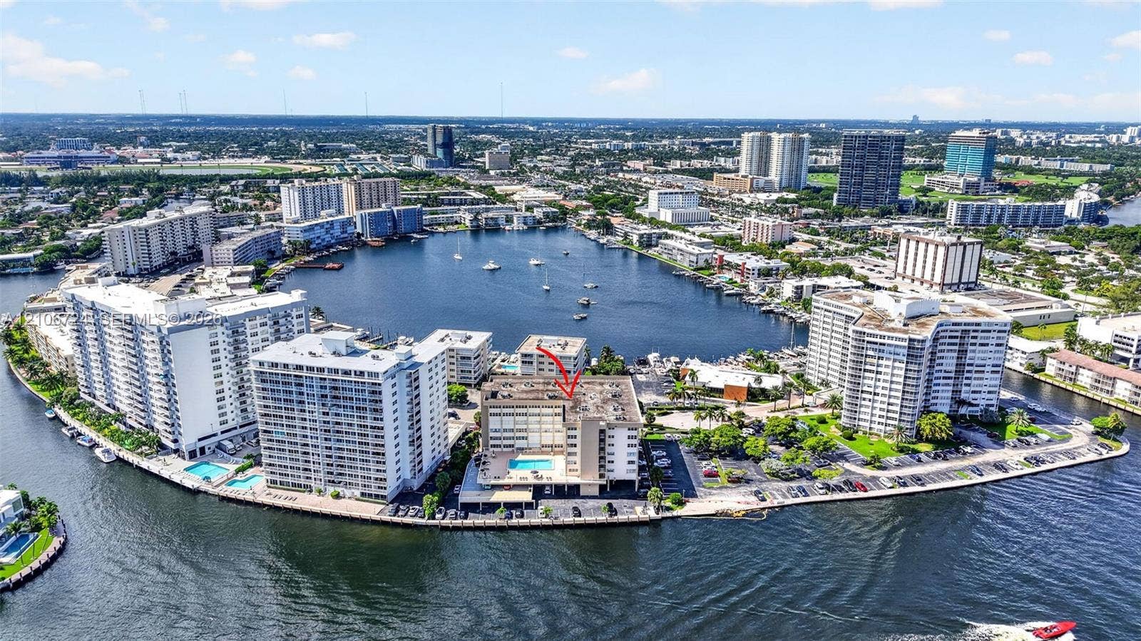 111 Golden Isles Drive, #G12, Hallandale Beach, FL 33009 Aerial perspective of waterfront mid-rise building featuring a swimming pool, bulkhead shoreline, and direct water access