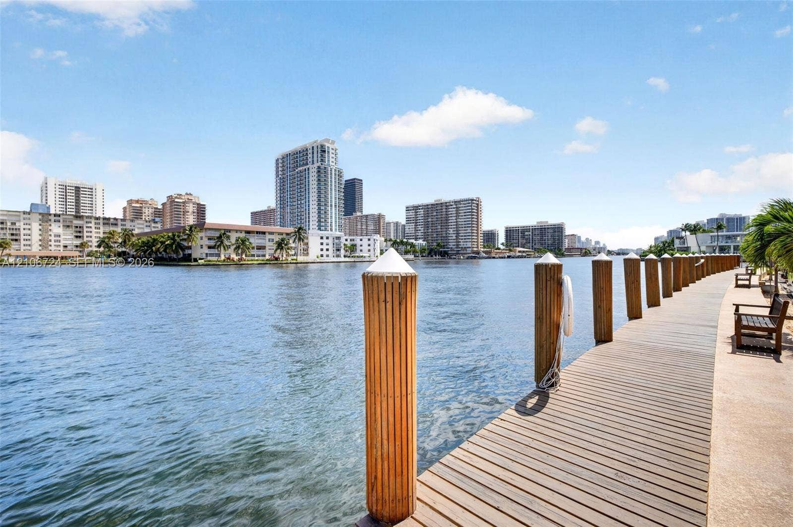 111 Golden Isles Drive, #G12, Hallandale Beach, FL 33009 Waterfront wooden dock featuring rounded pilings and a concrete walkway