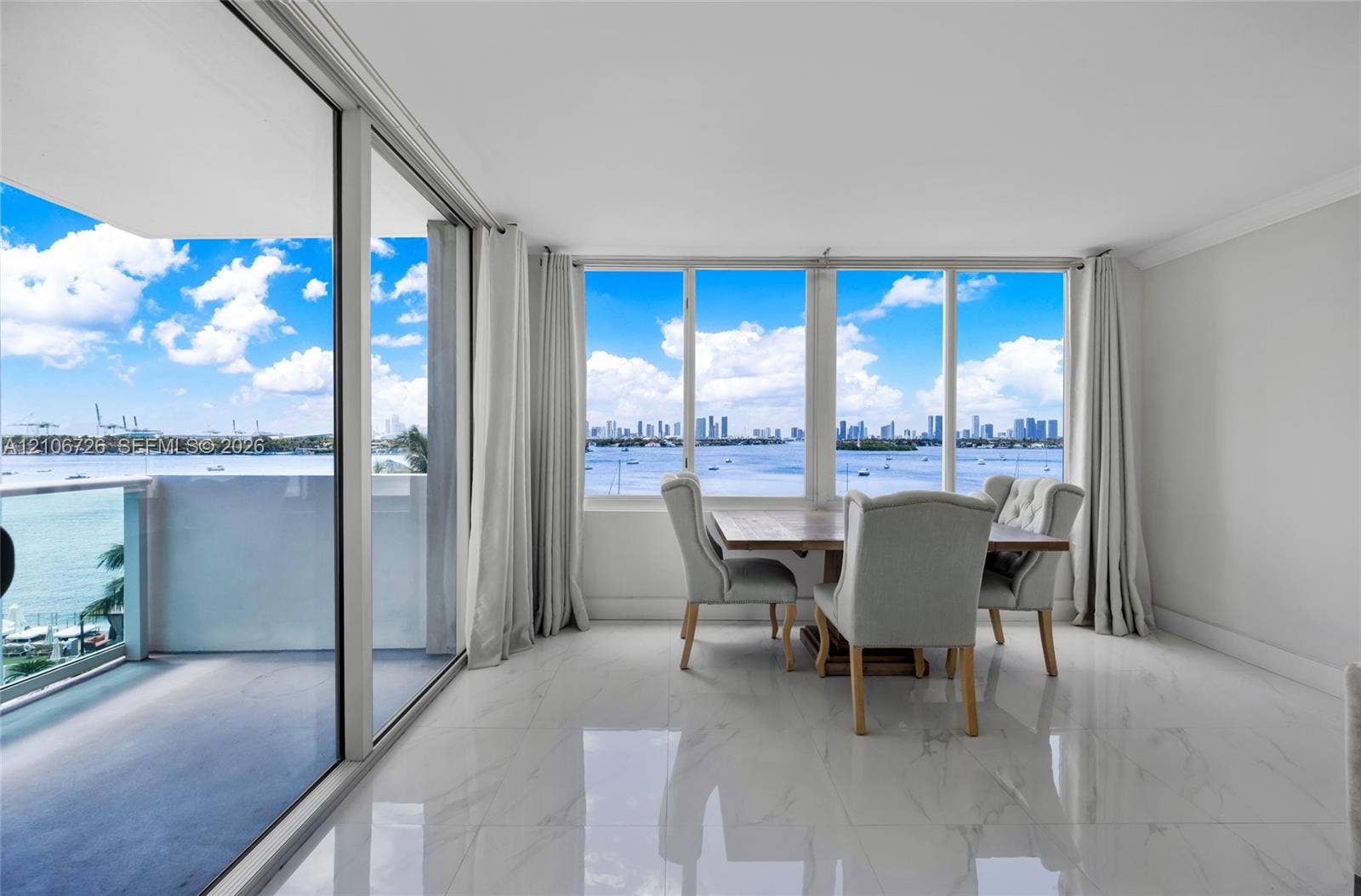 1200 West Avenue, #606, Miami Beach, Miami Beach, FL 33139 Floor-to-ceiling windows, polished stone-finish tile flooring, and sliding glass doors opening to a balcony with water and skyline scenery