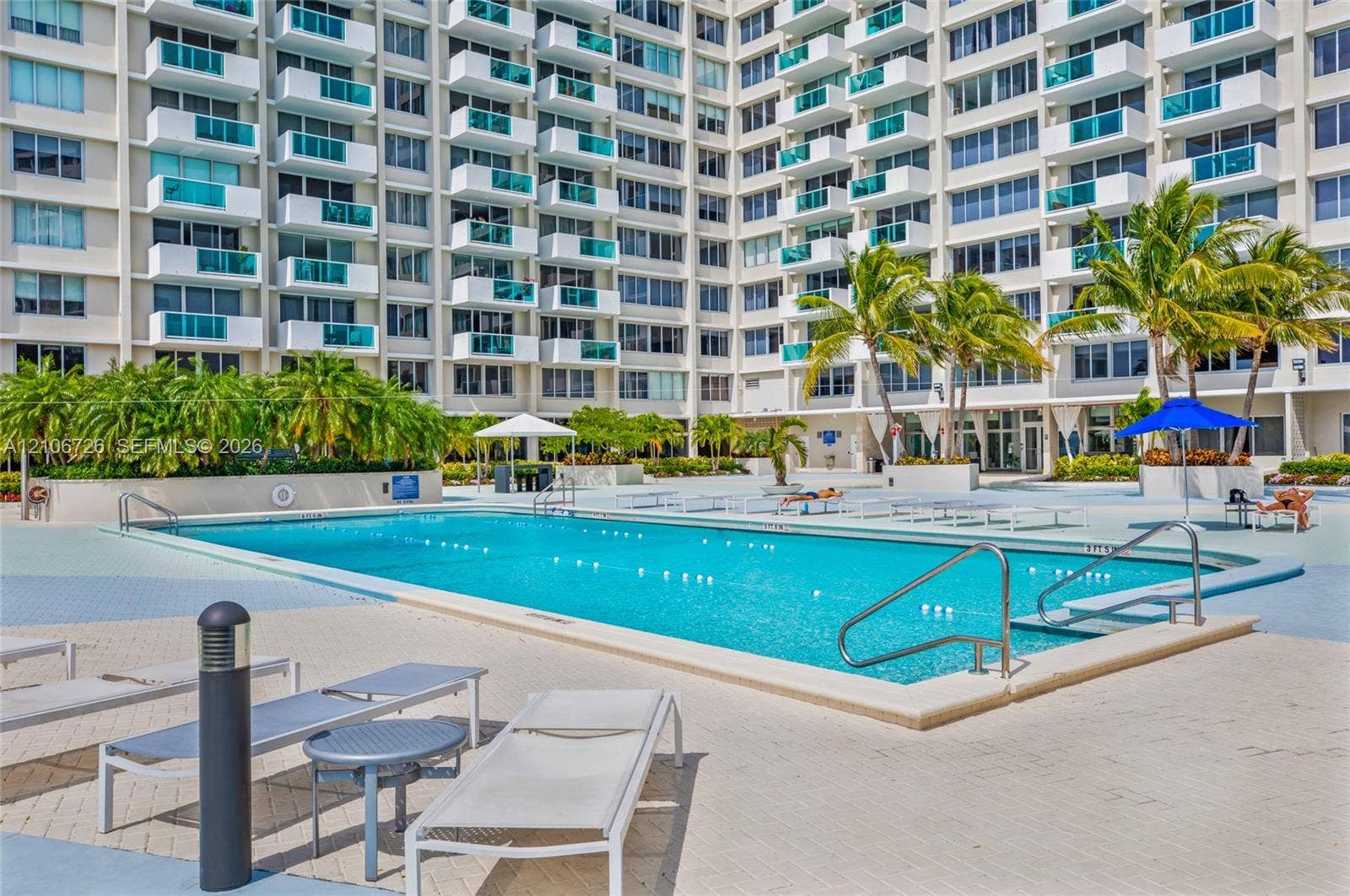 1200 West Avenue, #606, Miami Beach, Miami Beach, FL 33139 Swimming pool with metal handrails, paver pool deck, and integrated landscaping including palm trees