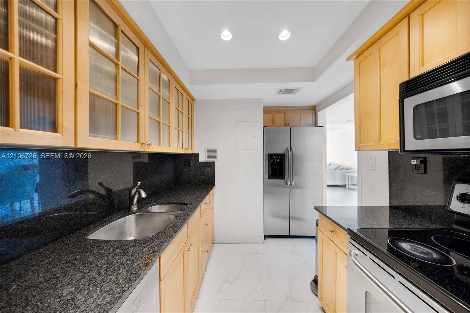 1200 West Avenue, #606, Miami Beach, Miami Beach, FL 33139 Kitchen featuring light-tone cabinetry with glass-paneled upper doors, dark stone countertops, stainless steel appliances, and large-format tile flooring