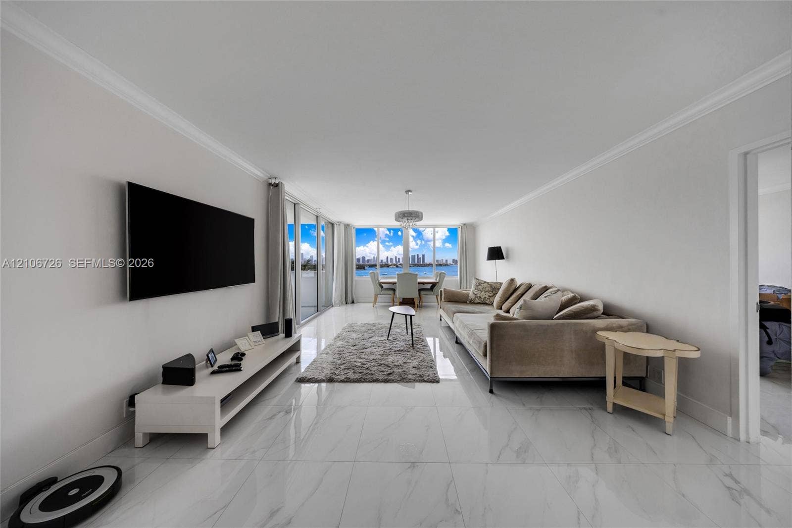 1200 West Avenue, #606, Miami Beach, Miami Beach, FL 33139 Open-concept living space featuring large-format tile flooring with marble-finish veining, floor-to-ceiling glass sliding doors, and water and city skyline backdrop