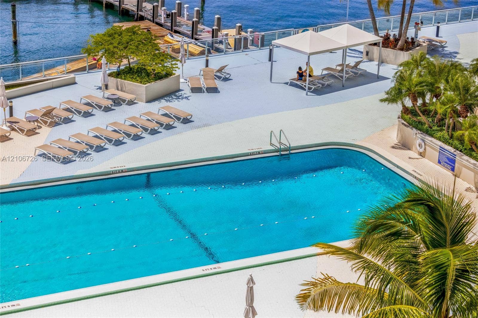 1200 West Avenue, #606, Miami Beach, Miami Beach, FL 33139 In-ground swimming pool with lane markers, paved deck, overhead poolside canopies, concrete planters with mature landscaping, and waterfront dock access