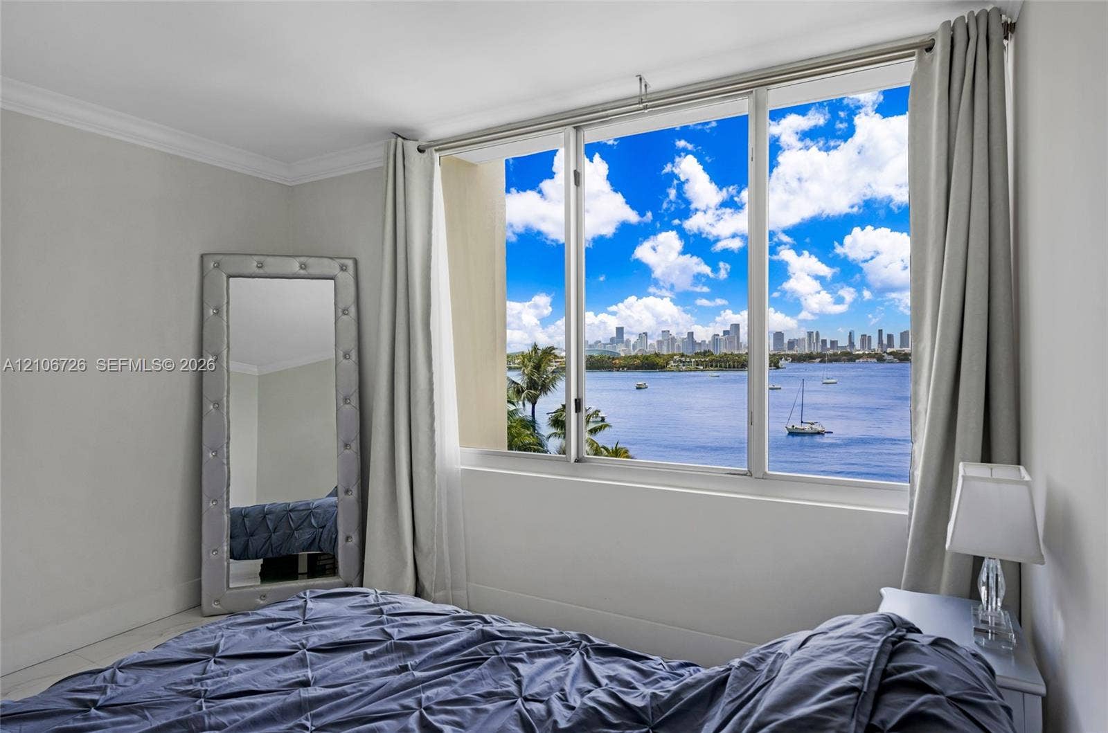 1200 West Avenue, #606, Miami Beach, Miami Beach, FL 33139 Expansive multi-pane window featuring a city skyline and water backdrop, complemented by crown molding and neutral-toned wall finish