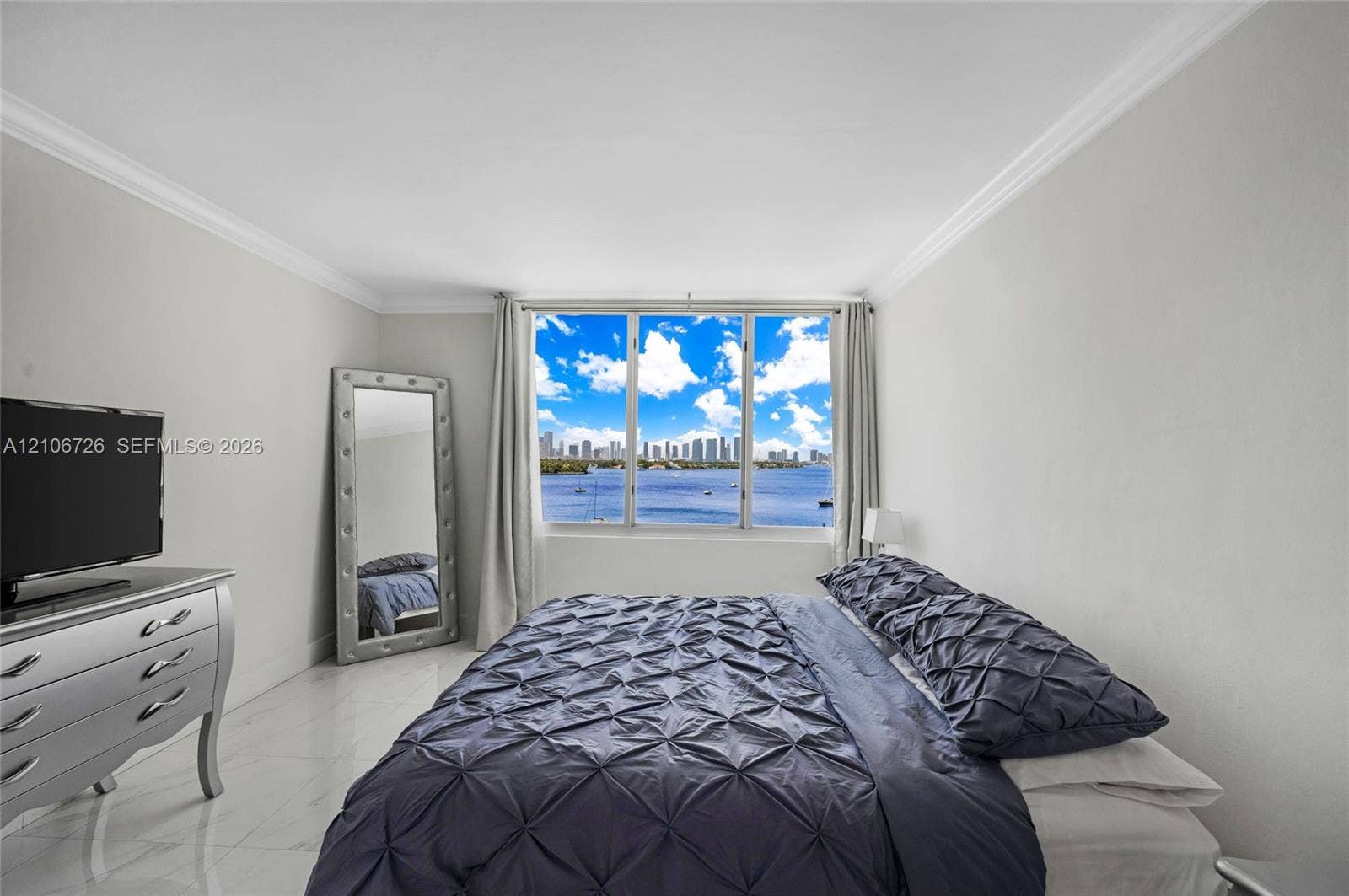 1200 West Avenue, #606, Miami Beach, Miami Beach, FL 33139 Large windows featuring a water and city skyline backdrop, polished tile flooring, and crown molding