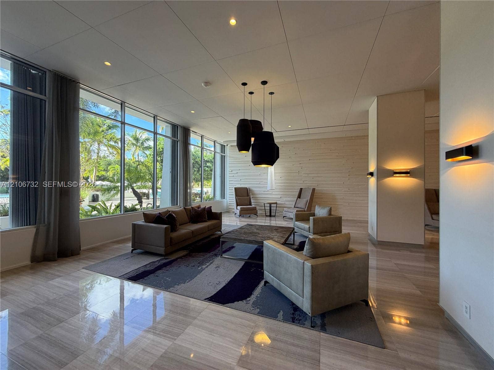Floor-to-ceiling windows, polished stone flooring, textured accent wall, integrated recessed lighting, and contemporary pendant fixtures