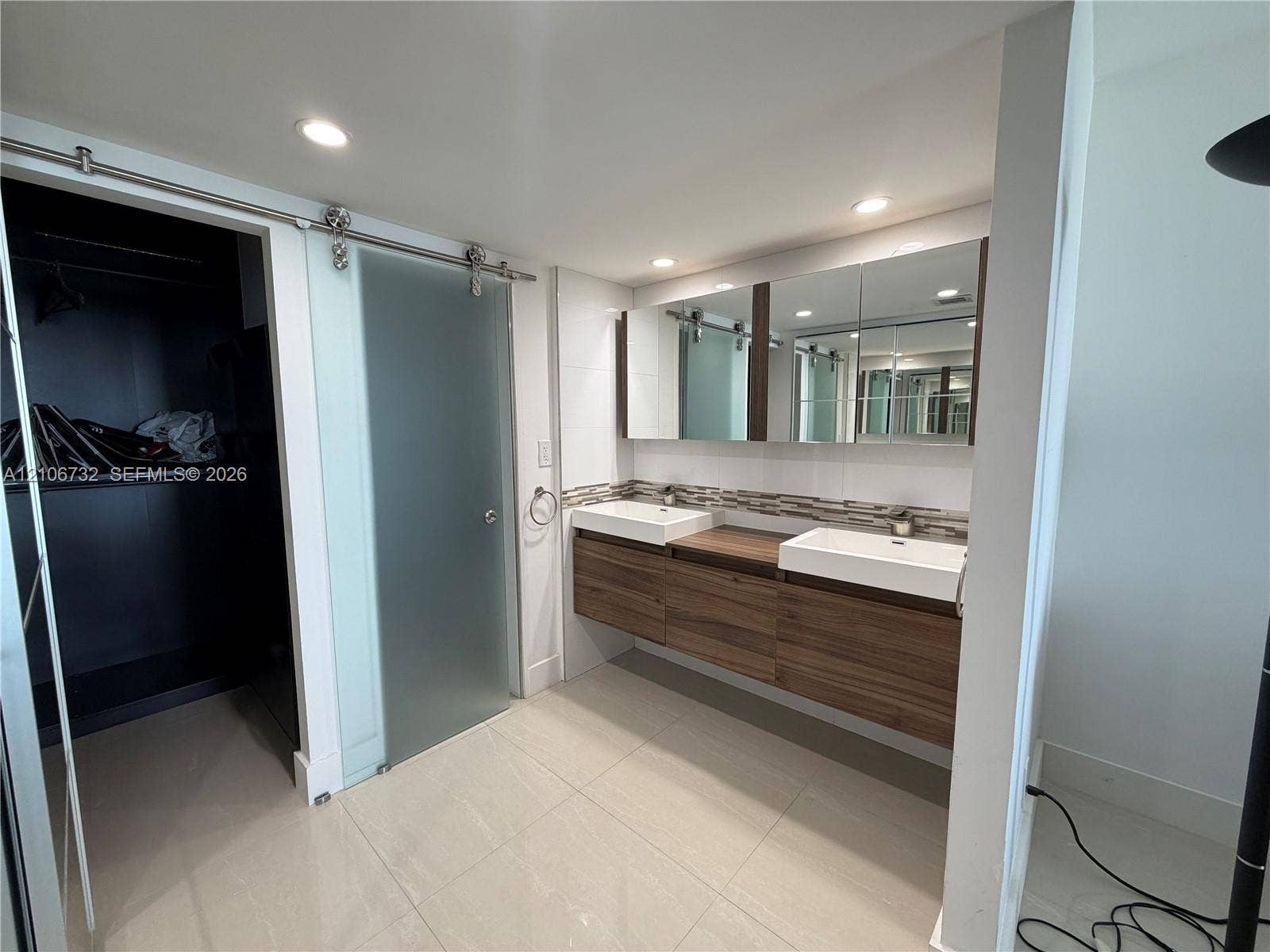 Floating dual vanity with wood-finish cabinetry, rectangular vessel sinks, recessed medicine cabinets, and frosted sliding glass door