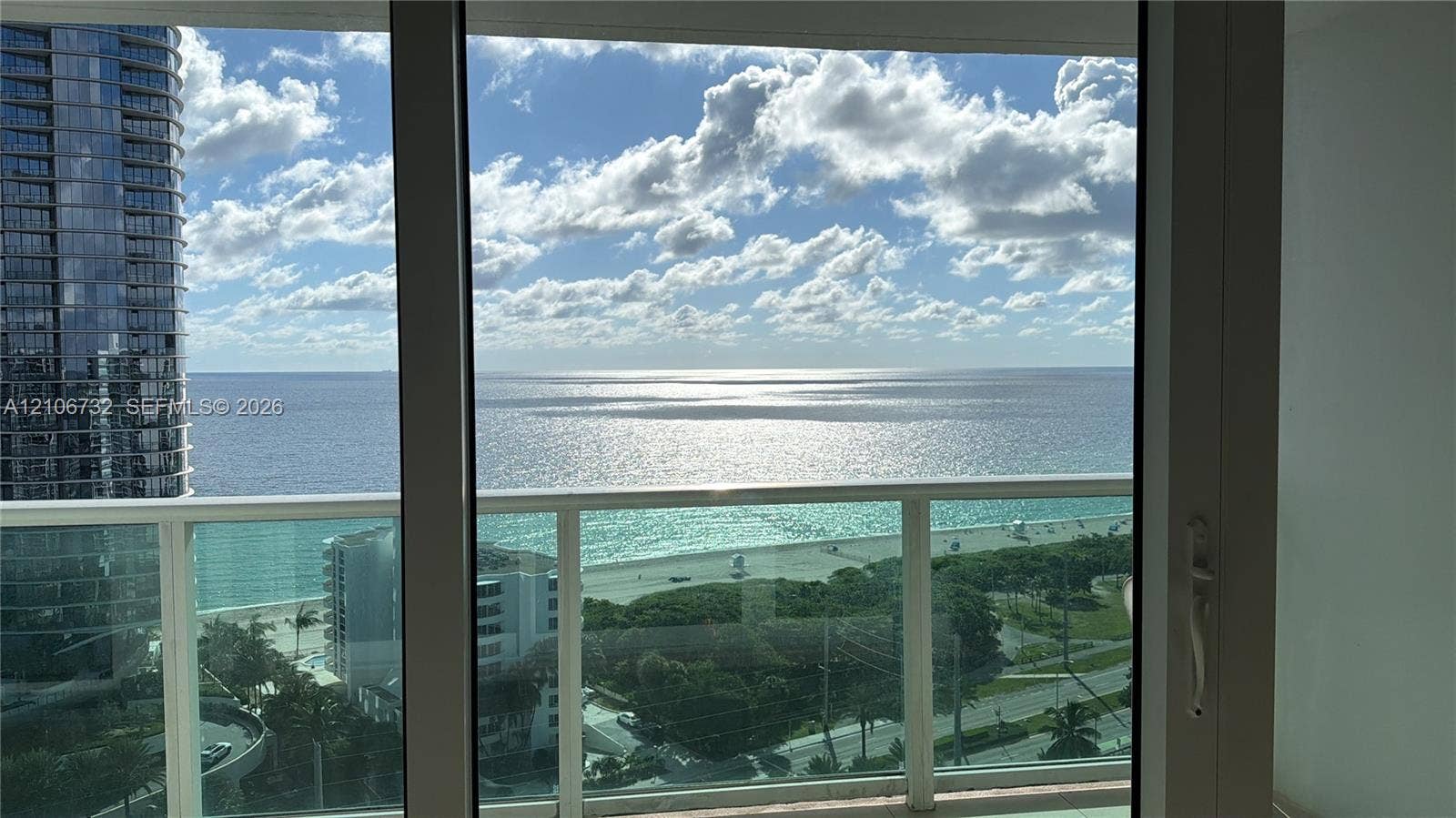 Floor-to-ceiling glass paneling and glass-railed balcony overlooking the ocean coastline