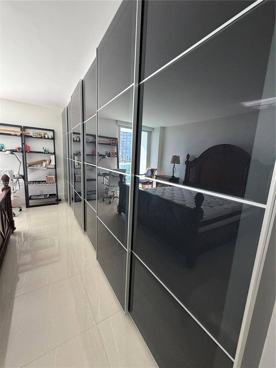 Floor-to-ceiling custom cabinetry with high-gloss charcoal panels and brushed metal framing, complemented by light-toned, large-format tile flooring