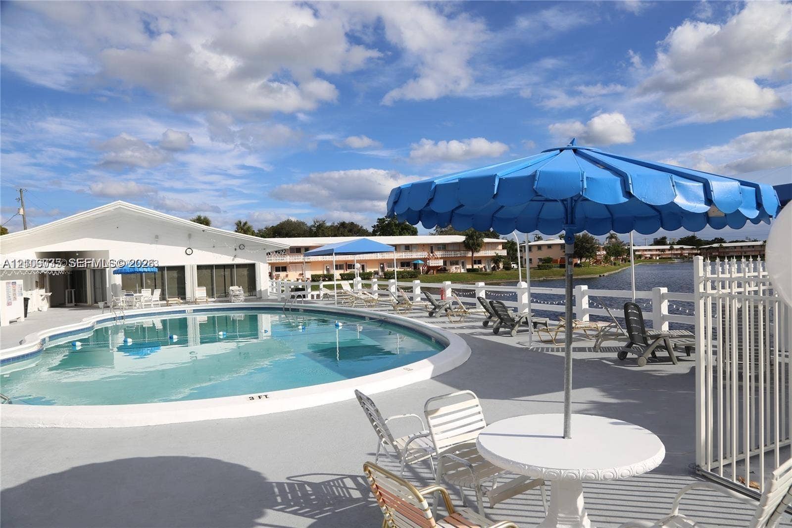 1000 SW 11 Avenue, #12, Hallandale Beach, Hallandale Beach, FL 33009 Outdoor swimming pool featuring concrete decking and white vinyl perimeter fencing, situated alongside a water feature