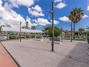 1000 SW 11 Avenue, #12, Hallandale Beach, Hallandale Beach, FL 33009 Outdoor recreational area featuring a paved court, built-in benches, overhead canopy, and exterior lighting fixtures
