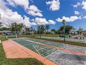 1000 SW 11 Avenue, #12, Hallandale Beach, Hallandale Beach, FL 33009 Outdoor shuffleboard courts featuring concrete playing surfaces and marked scoring zones, complemented by a manicured lawn and mature palm trees