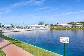 1000 SW 11 Avenue, #12, Hallandale Beach, Hallandale Beach, FL 33009 Large water feature bordered by a paved walkway and manicured green space, featuring a white perimeter fence and multi-story building structures