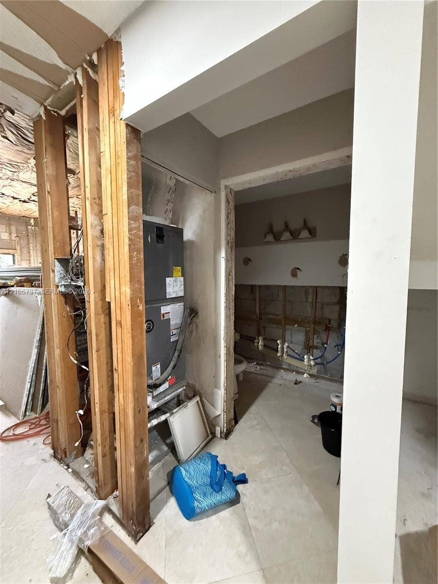 5225 Monterey Circle, #G, Delray Beach, FL 33484 Interior space featuring exposed wood framing, a vertical HVAC unit, large-format tile flooring, and exposed wall plumbing