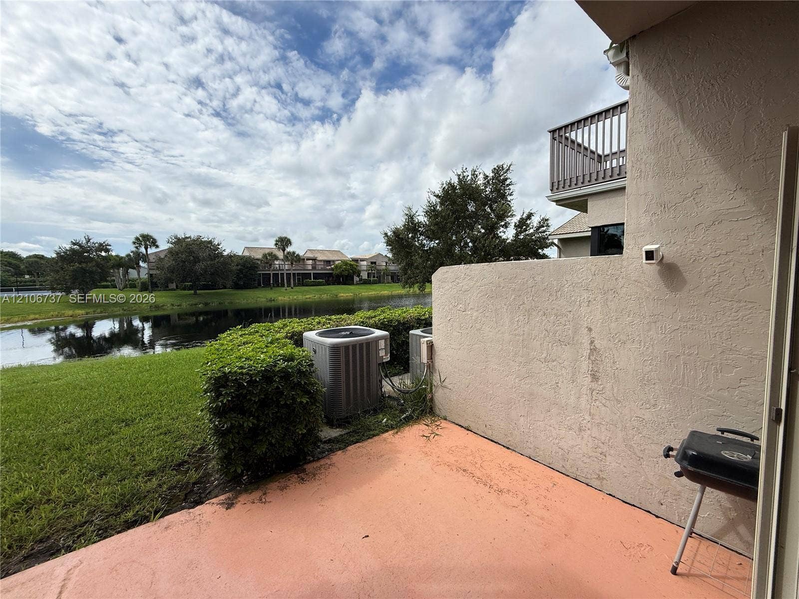 5225 Monterey Circle, #G, Delray Beach, FL 33484 Concrete patio featuring a stucco privacy wall, second-story balcony with railings, and water frontage