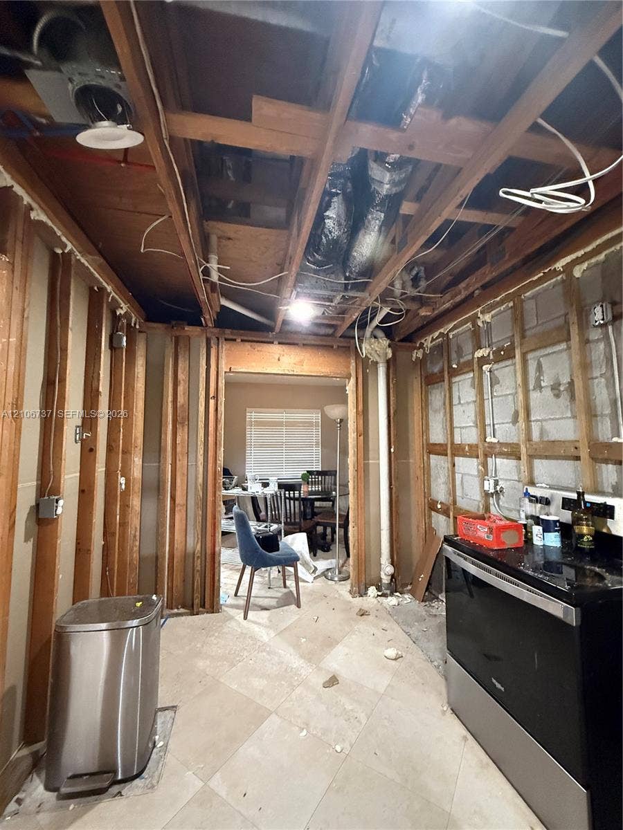 5225 Monterey Circle, #G, Delray Beach, FL 33484 Interior space featuring exposed wood framing, concrete block wall construction, tile flooring, and integrated black-finish range