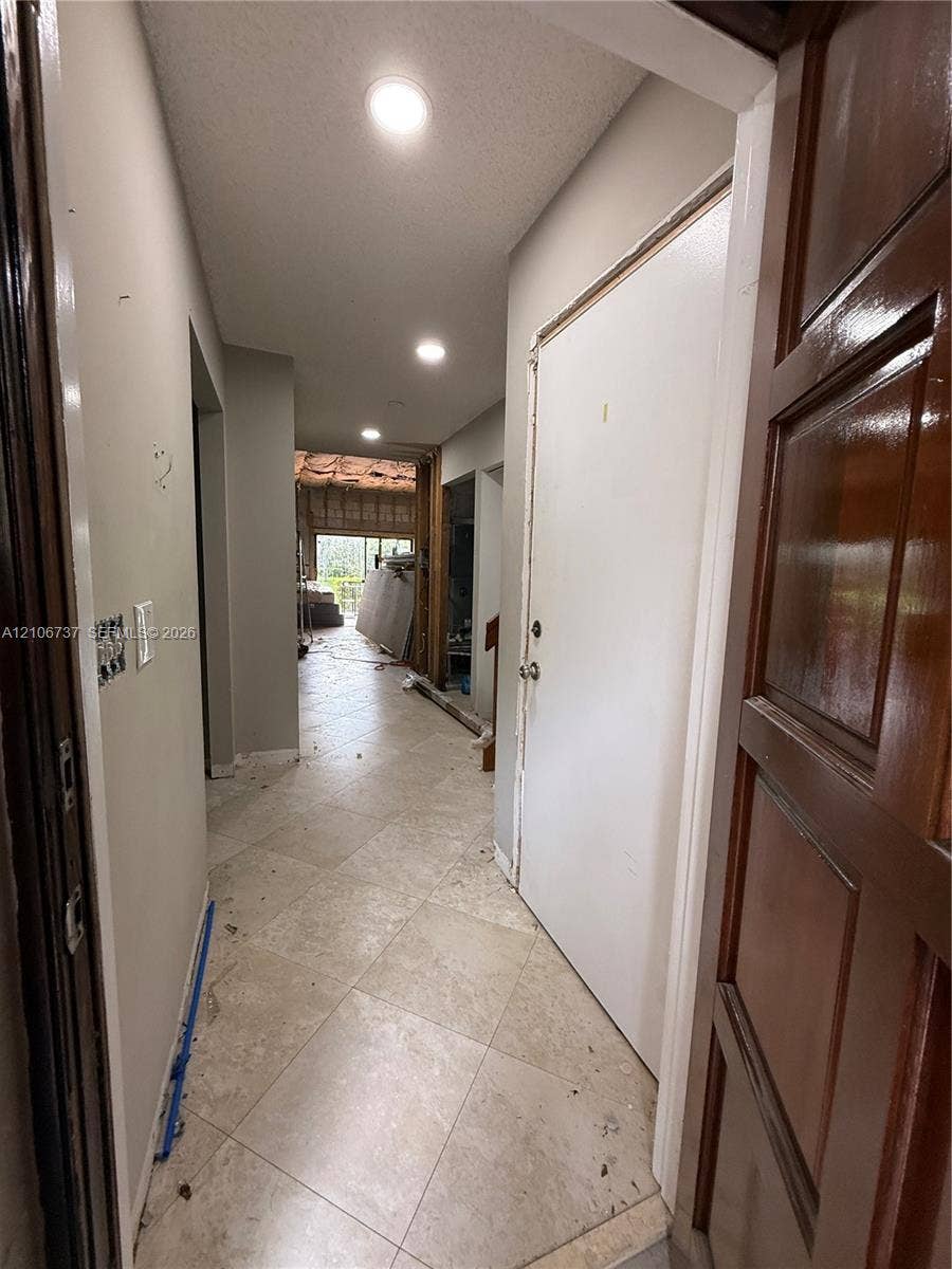 5225 Monterey Circle, #G, Delray Beach, FL 33484 Neutral-tone ceramic tile flooring laid in a diamond pattern, recessed lighting, and a six-panel wood door with a stained finish