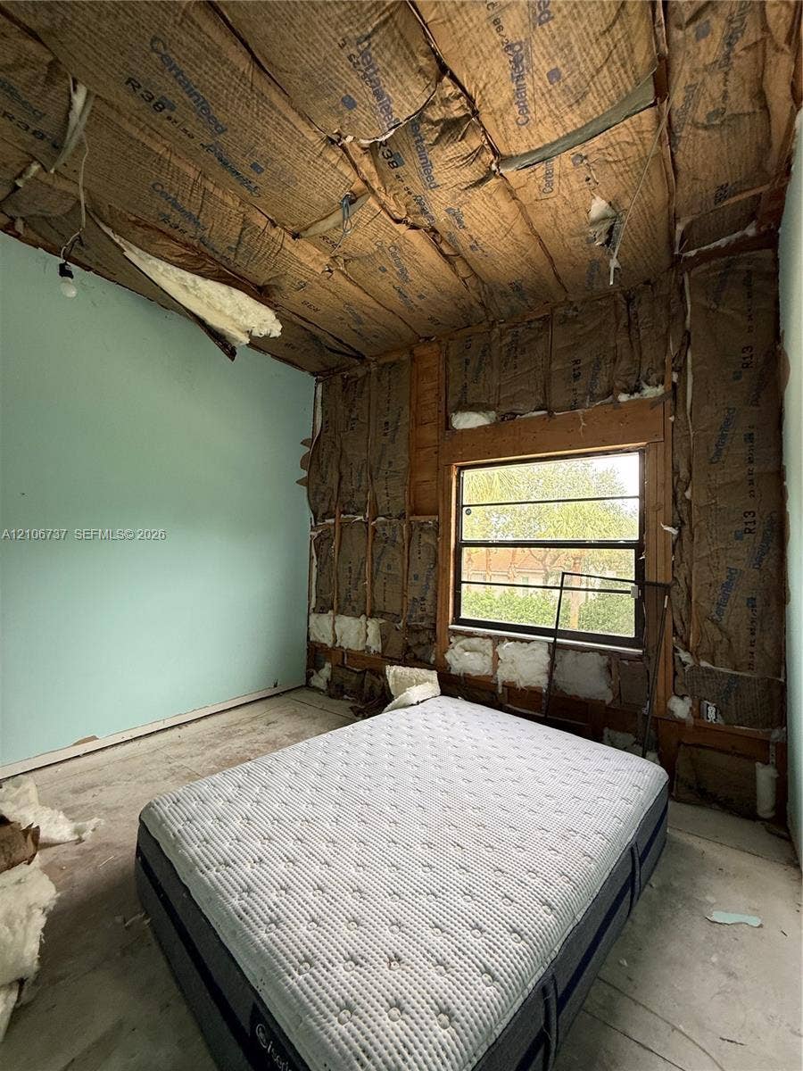 5225 Monterey Circle, #G, Delray Beach, FL 33484 Interior space featuring exposed fiberglass insulation, unfinished ceiling and wall surfaces, and a single-pane horizontal sliding window
