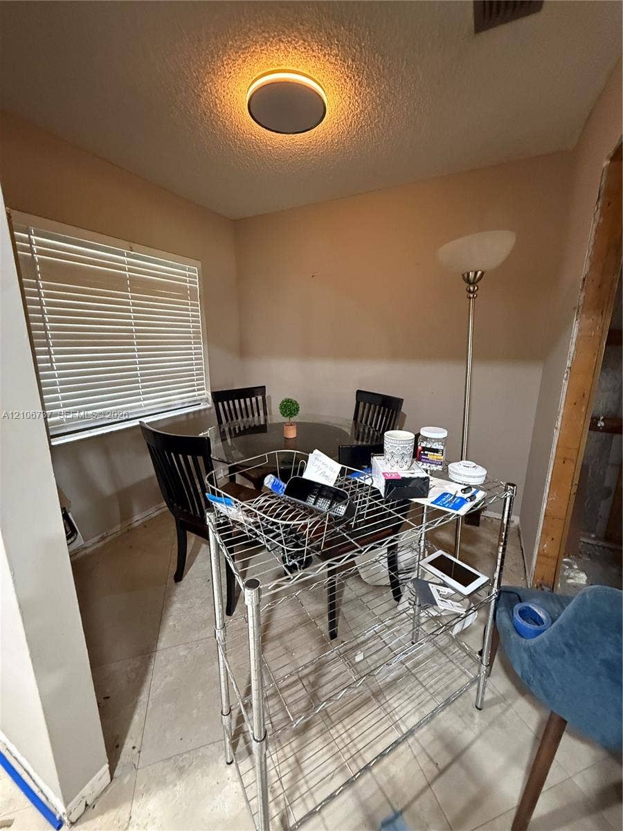 5225 Monterey Circle, #G, Delray Beach, FL 33484 Neutral-toned room featuring a window with horizontal blinds, neutral tile flooring, and a circular flush-mount ceiling light