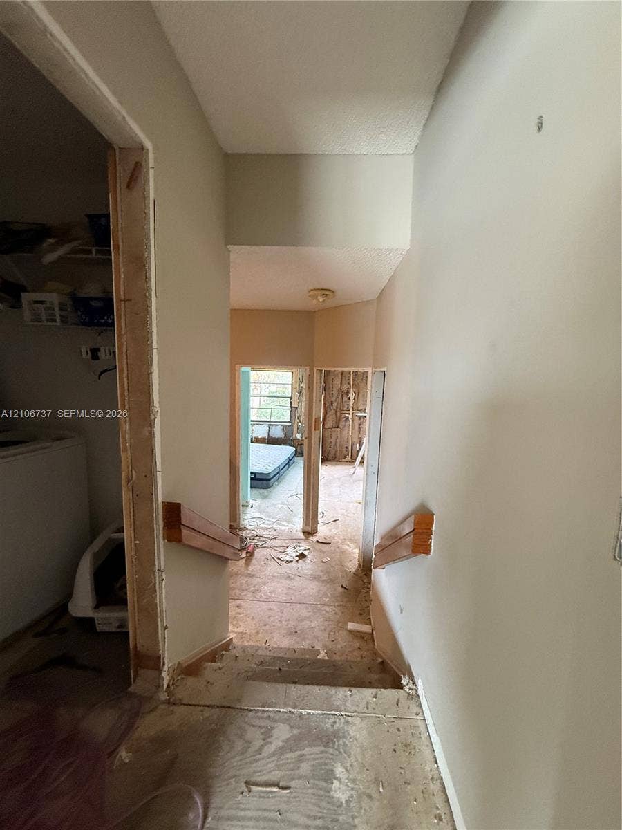5225 Monterey Circle, #G, Delray Beach, FL 33484 Interior staircase featuring wood-finish handrails and exposed subflooring