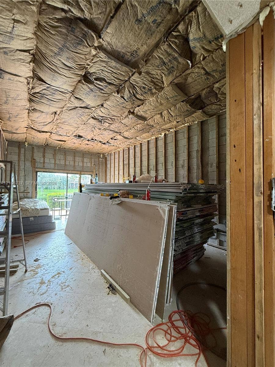 5225 Monterey Circle, #G, Delray Beach, FL 33484 Unfinished interior space featuring exposed concrete block wall construction, insulation-lined ceiling, and glass sliding door