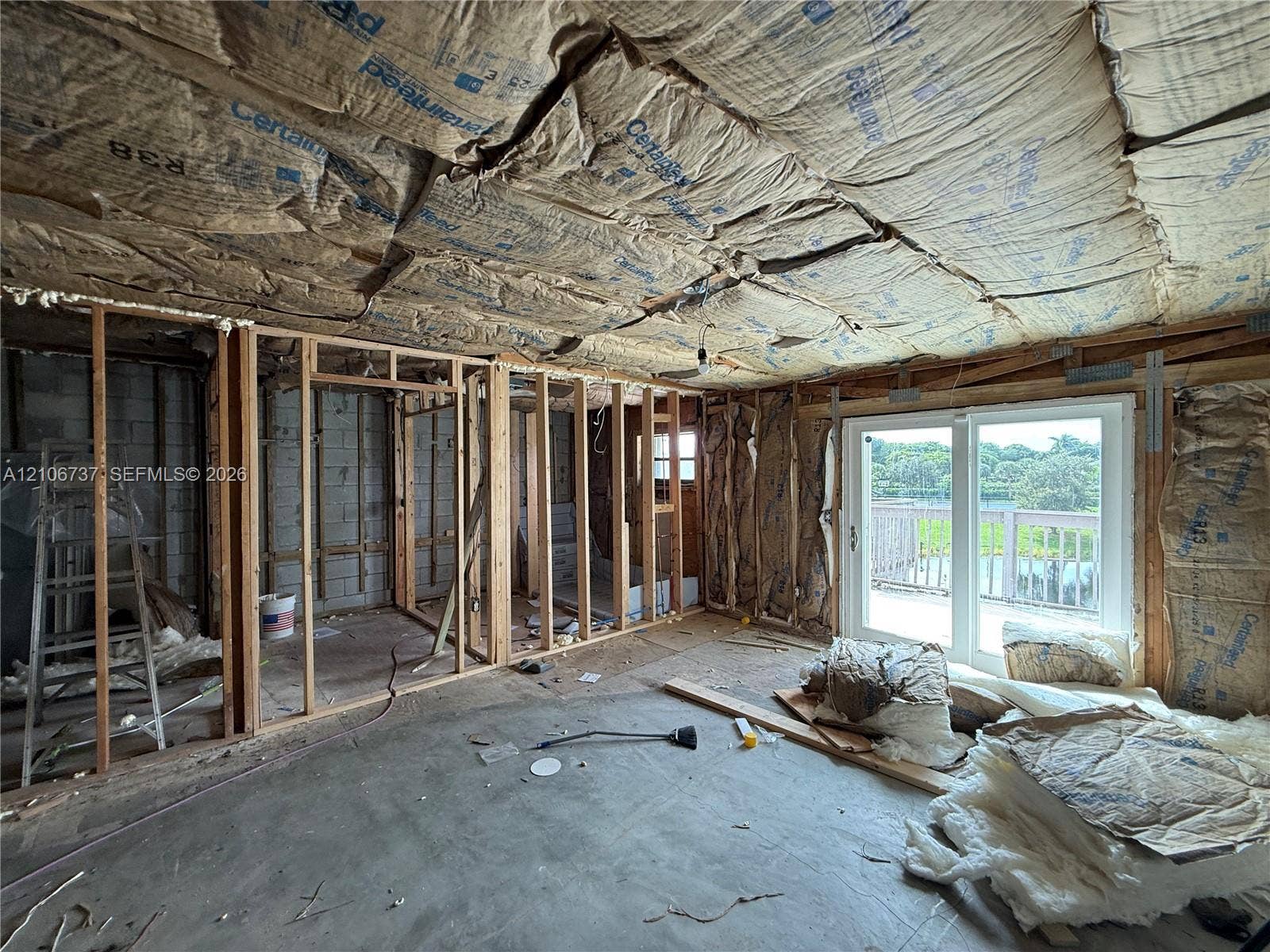 5225 Monterey Circle, #G, Delray Beach, FL 33484 Unfinished interior space featuring exposed wood framing, concrete flooring, and double-glass sliding doors opening to an exterior deck