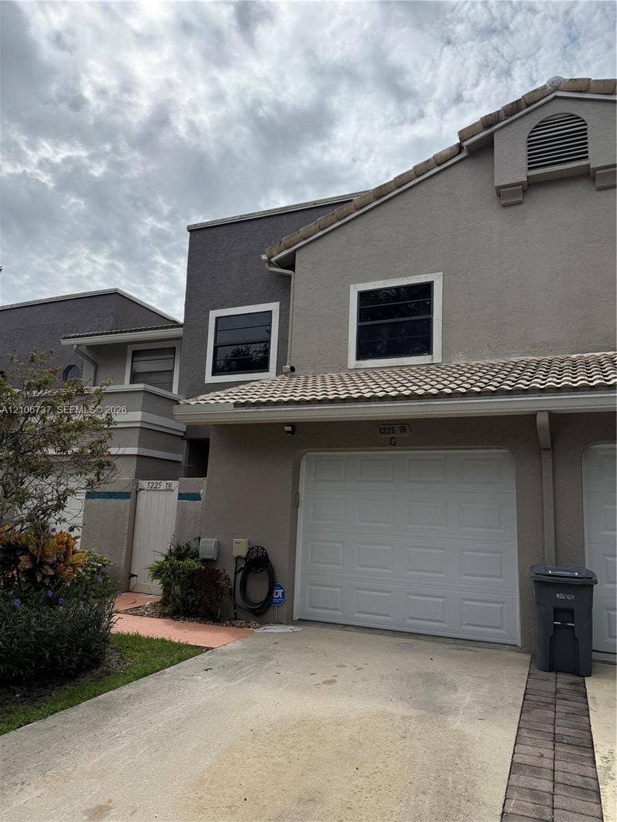 5225 Monterey Circle, #G, Delray Beach, FL 33484 Exterior featuring a stucco facade, tiled roof, attached garage, and paved driveway