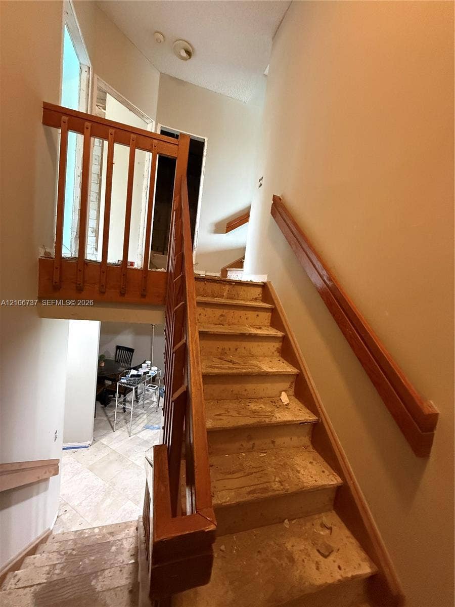 5225 Monterey Circle, #G, Delray Beach, FL 33484 Staircase featuring wood railings, balusters, and a wall-mounted handrail