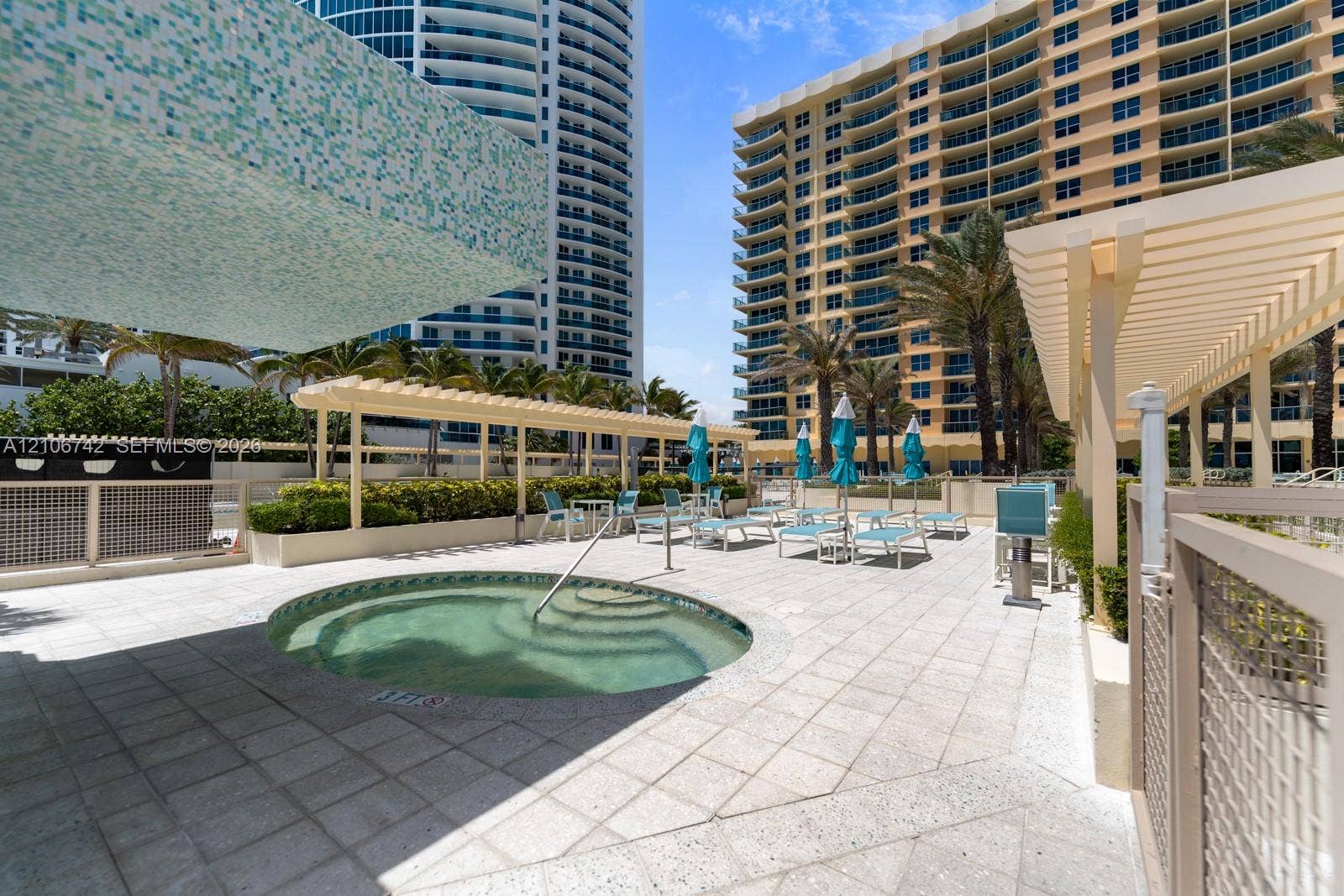 Circular spa with stone tile decking, wooden pergolas, and integrated landscaping
