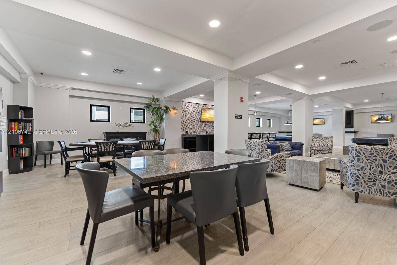 Open-concept interior featuring light wood-finish flooring, recessed lighting, and textured accent wall paneling