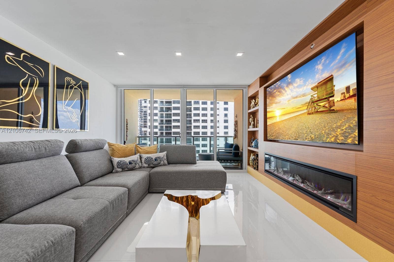 Living area featuring floor-to-ceiling glass sliding doors, polished tile flooring, recessed lighting, and a custom wood-paneled wall unit with an integrated linear electric fireplace and built-in display shelving