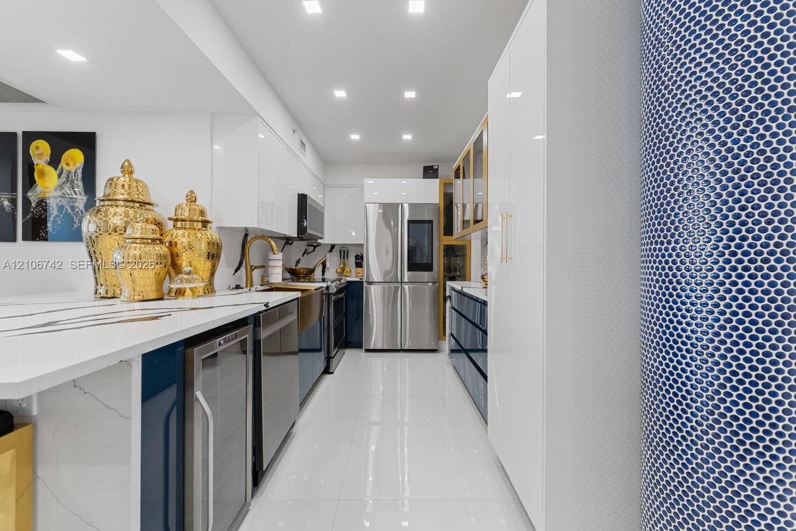 Kitchen featuring high-gloss cabinetry, stone-finish countertops, stainless steel appliances, recessed lighting, and a textured tile column