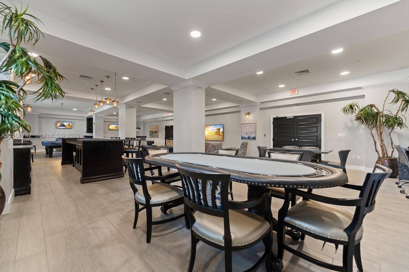 Open-concept recreation area featuring wood-finish flooring, recessed lighting, crown molding, and a built-in wet bar with dark cabinetry
