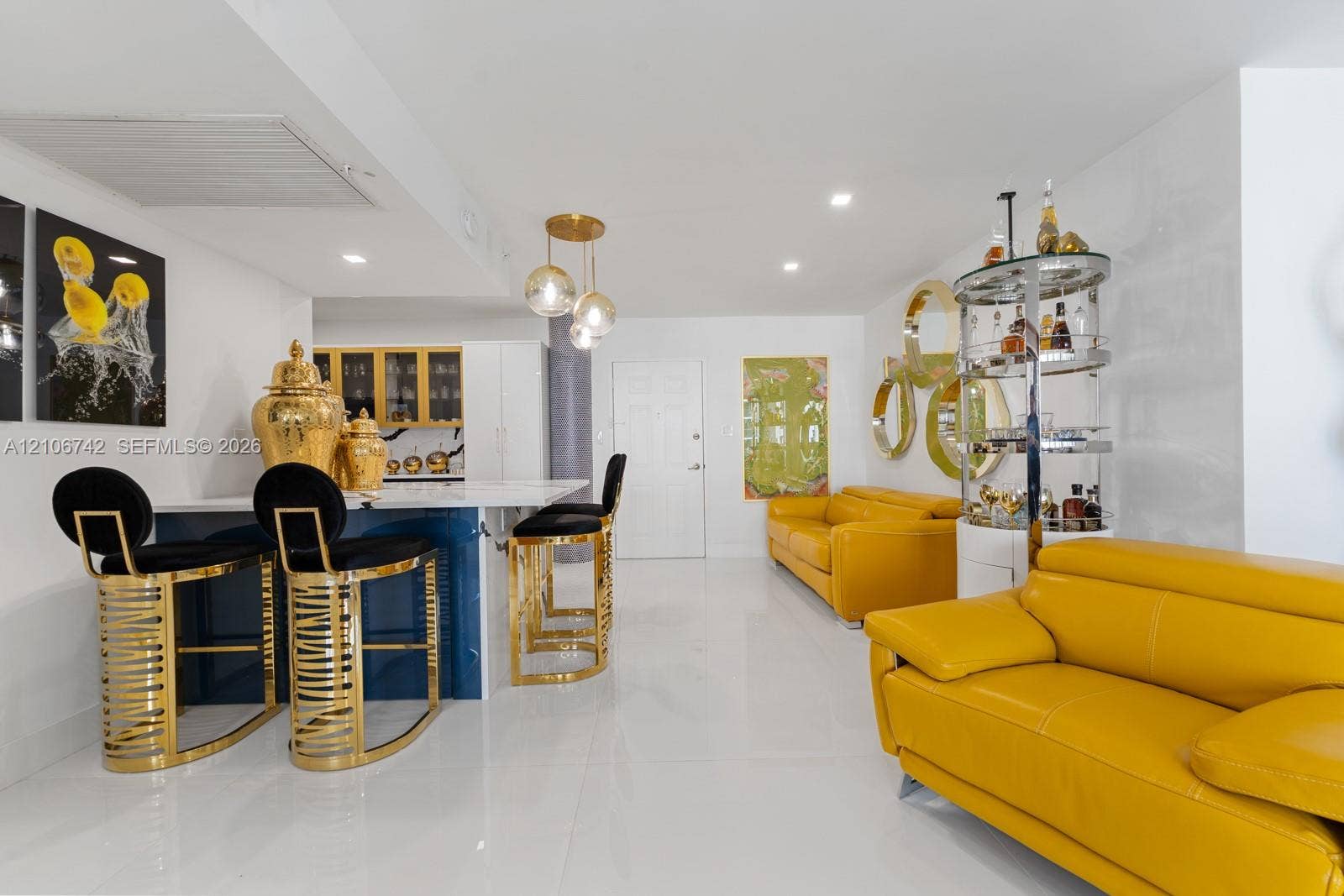 Kitchen featuring a center island with a solid surface countertop, glass-globe pendant lighting, built-in cabinetry with glass-front uppers, and large-format polished flooring